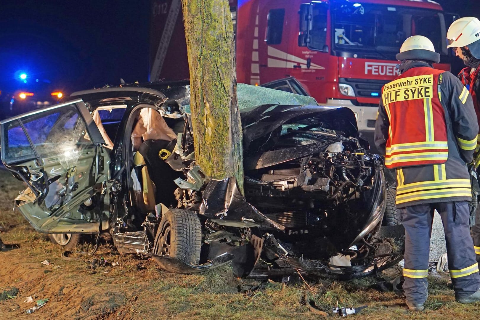 Feuerwehrleute stehen neben dem völlig zerstörten Auto: Warum der Wagen von der Straße abkam, ist völlig unklar.