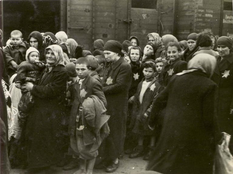 Frauen und Kinder warten nach der Ankunft in Auschwitz auf die Befehle der SS-Leute.