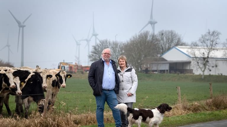 Hermann Oldewurtel und Insa Bock stehen vor den Windkraftanlagen hinter ihrem Wohnhaus in Holtgast.