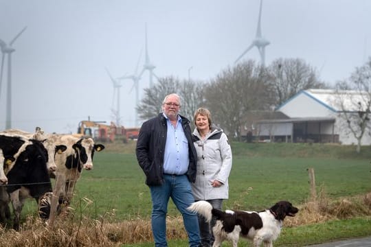 Hermann Oldewurtel und Insa Bock stehen vor den Windkraftanlagen hinter ihrem Wohnhaus in Holtgast.
