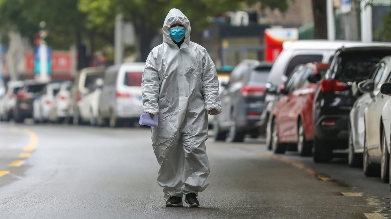 Ein Mitarbeiter des chinesischen Seuchenschutzes läuft in Schutzkleidung über die Straßen Wuhans.