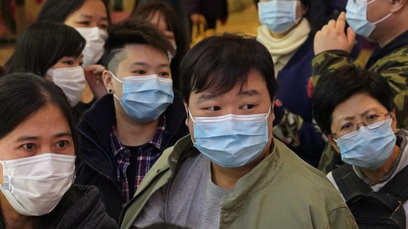 Menschen warten vor einem Geschäft in Hongkong, um Atemschutzmasken zu kaufen.