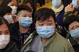 Menschen warten vor einem Geschäft in Hongkong, um Atemschutzmasken zu kaufen.