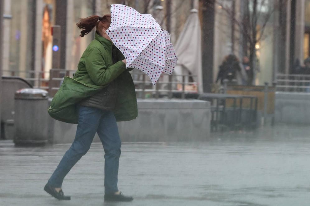 Eine Frau kämpft mit ihrem Regenschirm gegen einen heftigen Schauer: Als erstes trifft "Lolita" auf Baden-Württemberg. (Symbolbild)