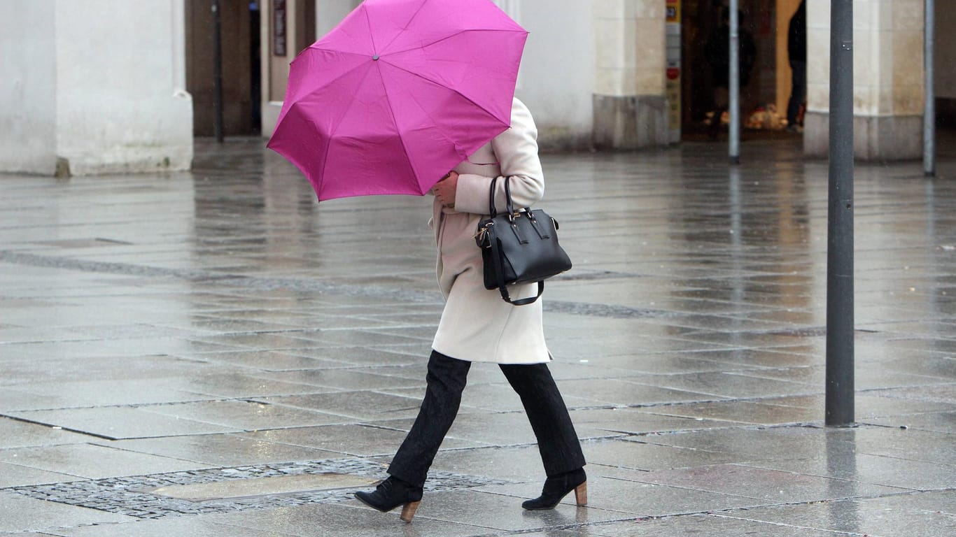 Frau mit Regenschirm: Noch bis in die Nacht zum Donnerstag wütet Sturmtief Lolita über Deutschland. Zum Wochenende wird es milder.