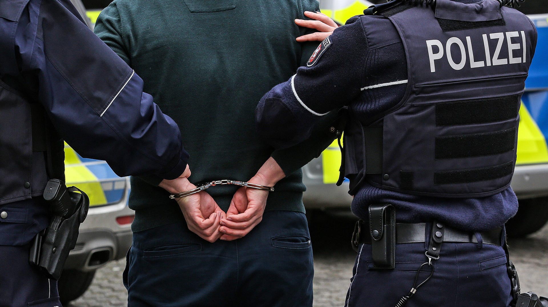 Zwei Polizisten mit einer Person in Handschellen: In Hagen ist ein mutmaßlicher Feuerteufel gefasst worden (Symbolbild).