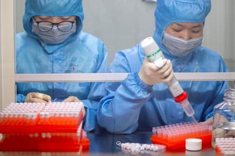 Mitarbeiter in Schutzkleidung stellen Tests zur Feststellung des Coronavirus her: Der Ausbruch der neuen Lungenkrankheit sorgt für zahlreiche Verschwörungstheorien.