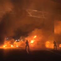 Feuerwehrleute löschen die brennende Fahrzeuge: Der Fahrer des Geldtransporters konnte flüchten.