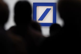 Deutsche Bank: Aktionäre sitzen während einer Hauptversammlung der Deutschen Bank in der Frankfurter Festhalle vor dem Unternehmenslogo.