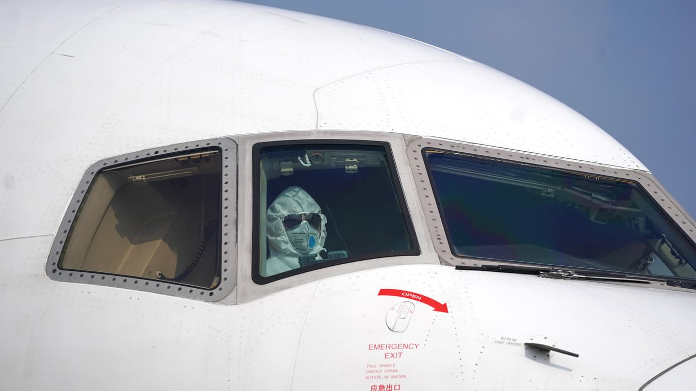 Ein Pilot sitzt mit Schutzanzug auf dem Internationalen Flughafen in Wuhan: Auch in China versucht man mit Schutzmaßnahmen dem Virus Herr werden.