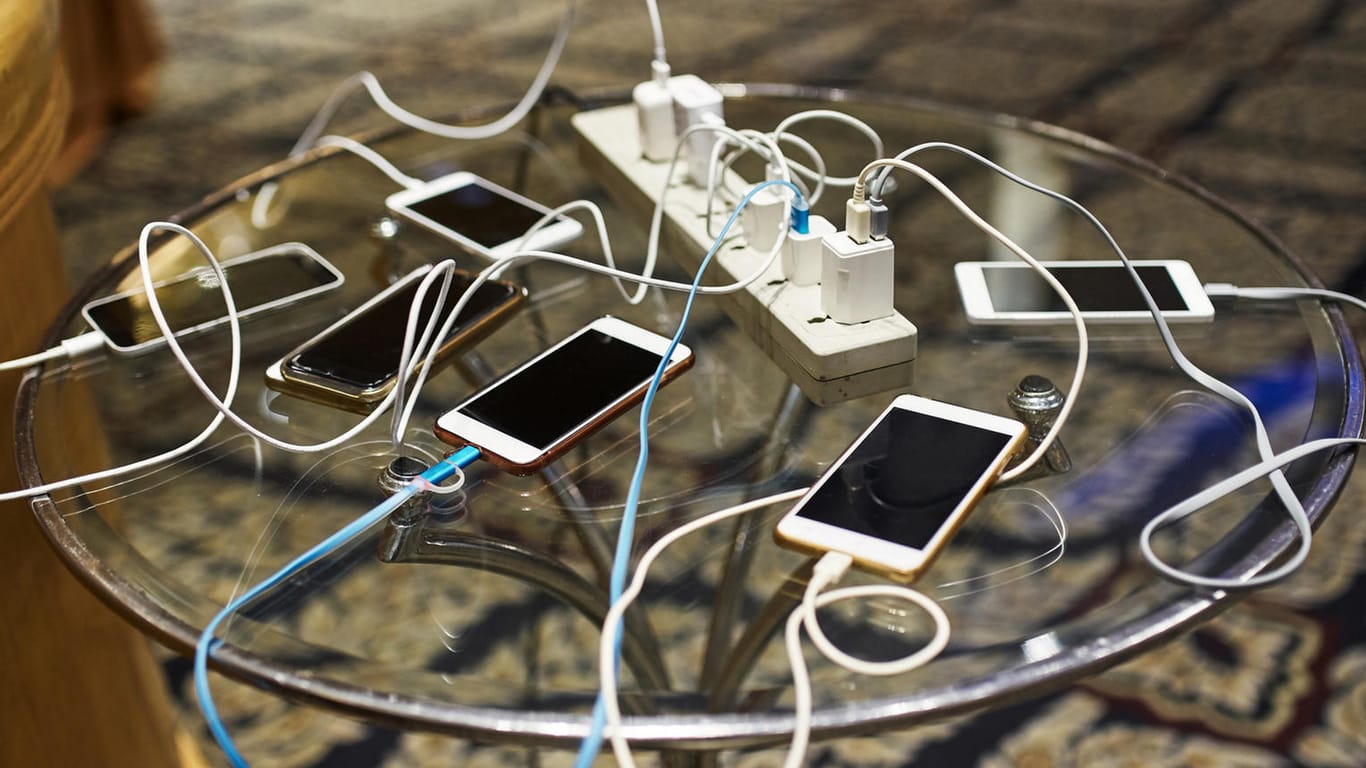 Smartphones werden auf einem Tisch geladen (Symbolbild): Die EU will für Elektrogeräte einheitliche Ladekabel.