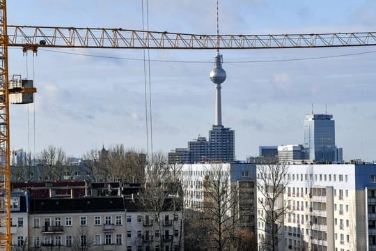 Der Fernsehturm am Alexanderplatz ist hinter Baukränen und Mietshäusern zu sehen.