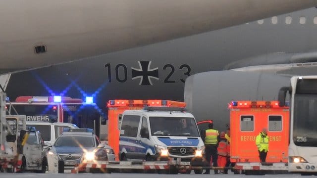 Rettungskräfte und Polizisten stehen neben dem Flugzeug bereit.