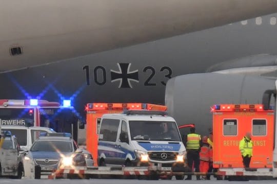 Rettungskräfte und Polizisten stehen neben dem Flugzeug bereit.