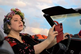 Miss Cherry Wine schießt in einem Auto ein Selfie.