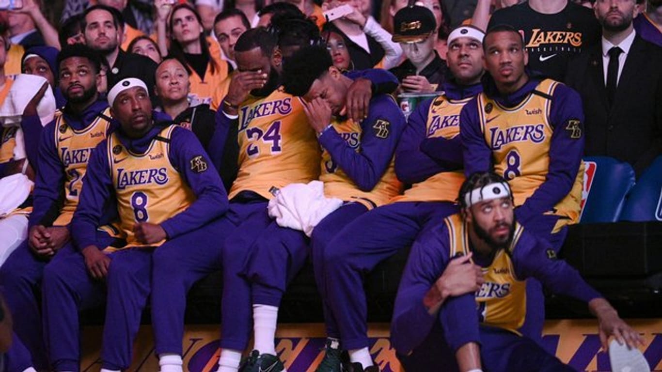 LeBron James (M,l) und Quinn Cook (M,r) von den Los Angeles Lakers schlagen bei einem Video-Beitrag über Kobe Bryant die Hände vors Gesicht.