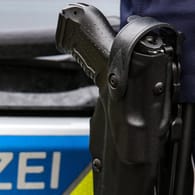 Ein Polizist mit Waffe steht vor einem Einsatzfahrzeug: Aus Viernheim floh der Verdächtige ins benachbarte Mannheim, wo er schließlich gestellt wurde (Symbolbild).