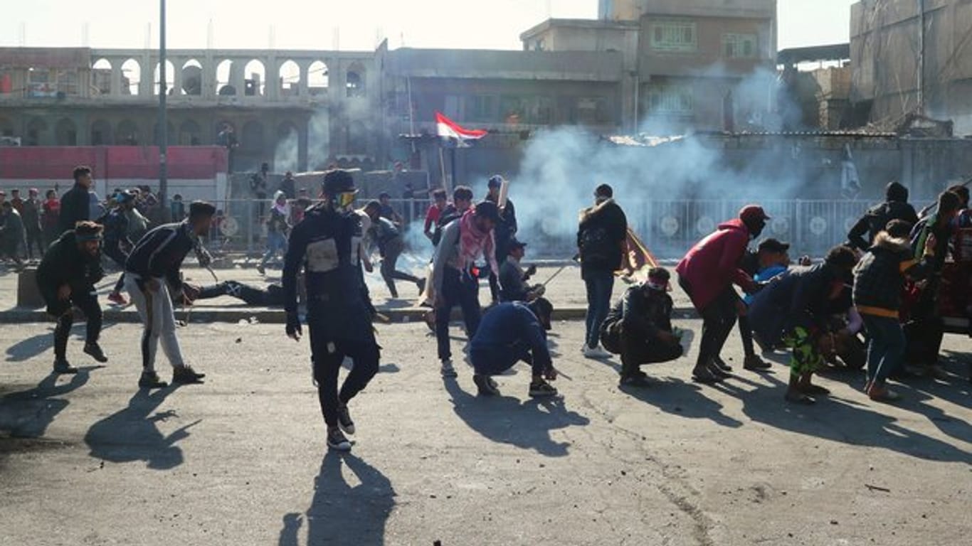 Demonstranten in Bagdad gehen vor Tränengasgeschossen in Deckung.