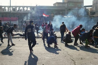 Demonstranten in Bagdad gehen vor Tränengasgeschossen in Deckung.