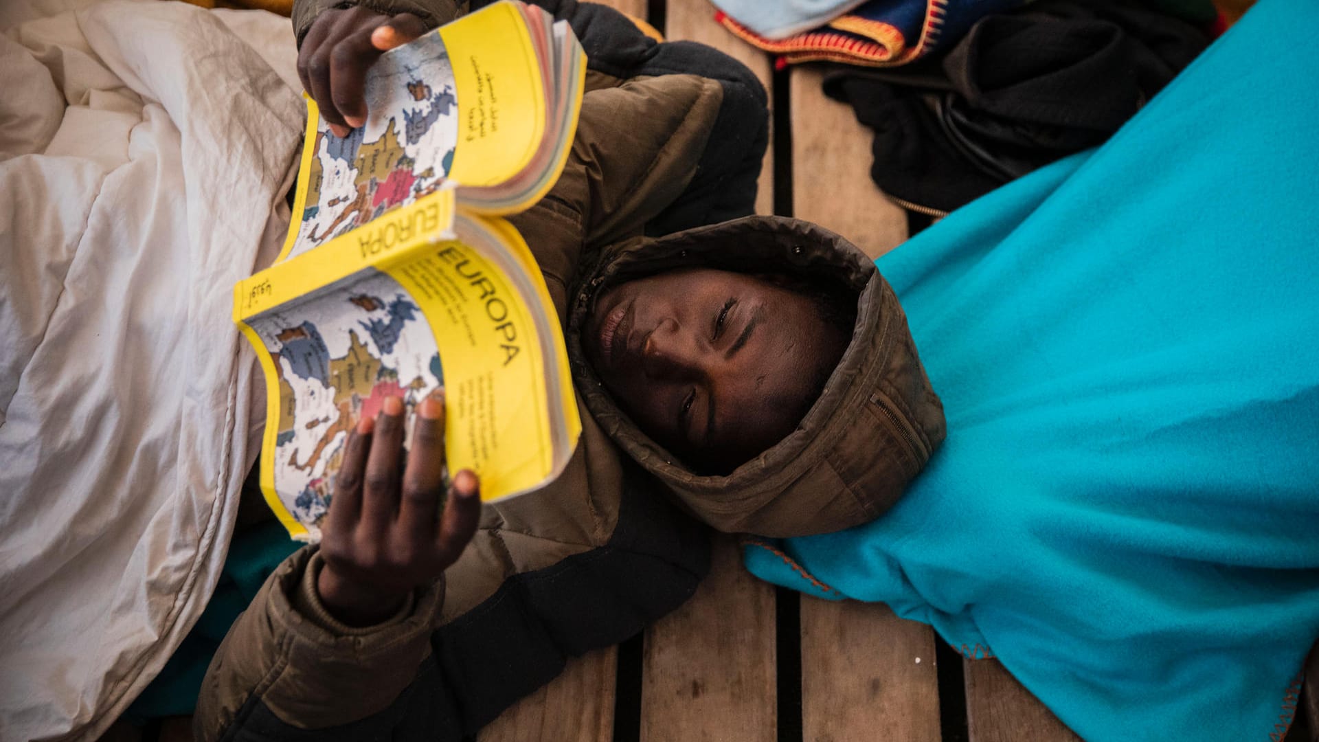 Gauro, 15, aus Mali, liest an Bord des Rettungsschiffes "Open Arms" ein Buch über Europa: Die Migranten mussten mehrere Tage auf die Genehmigung zum Einlaufen der "Open Arms" warten.