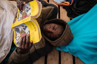 Gauro, 15, aus Mali, liest an Bord des Rettungsschiffes "Open Arms" ein Buch über Europa: Die Migranten mussten mehrere Tage auf die Genehmigung zum Einlaufen der "Open Arms" warten.