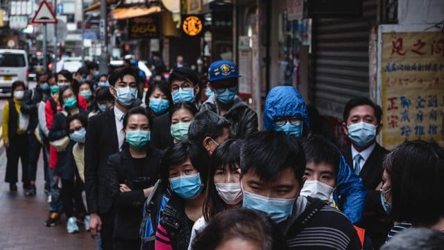Anwohner warten in Hongkong auf eine Lieferung von chirurgischen Masken, die in einem nahe gelegenen Laden verkauft werden. Anwohner warten in Hongkong auf eine Lieferung von chirurgischen Masken, die in einem nahe gelegenen Laden verkauft werden.