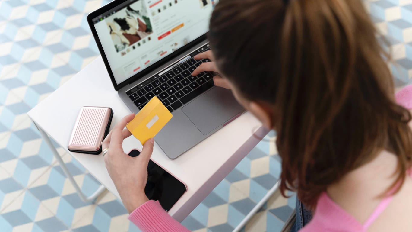 Eine Frau sitzt vor einem Laptop und kauft in einem Onlineshop ein (Symbolbild): Onlineshops informieren Käufer nicht ausreichend über ihre Rechte.