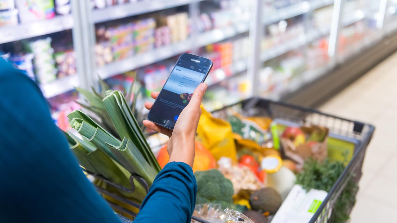 Eine Frau lässt sich auf ihrem Smartphone die von ihr gekauften Produkte anzeigen (Symbolfoto). Self-Scanning-Syteme machen die Supermarktkasse überflüssig.
