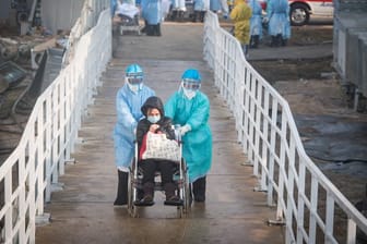 Mediziner helfen Corona-Patienten in Wuhan beim Umzug in die Isolierstationen eines neuen Behelfskrankenhauses mit rund tausend Betten.