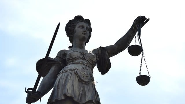 Eine Bronzestatue der Justitia steht unter freiem Himmel