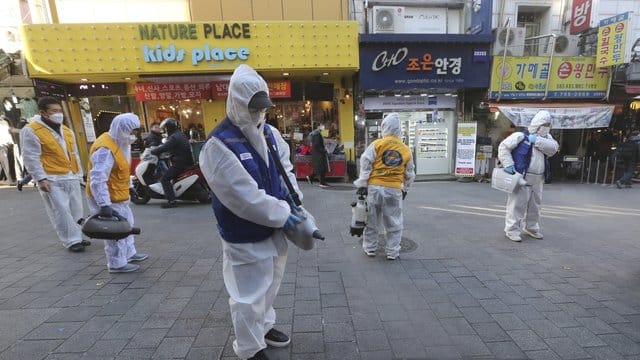 Arbeiter in Schutzkleidung versprühen auf einem Markt in Seoul Desinfektionsmittel. Arbeiter in Schutzkleidung versprühen auf einem Markt in Seoul Desinfektionsmittel.