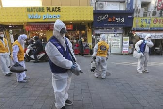 Arbeiter in Schutzkleidung versprühen auf einem Markt in Seoul Desinfektionsmittel.