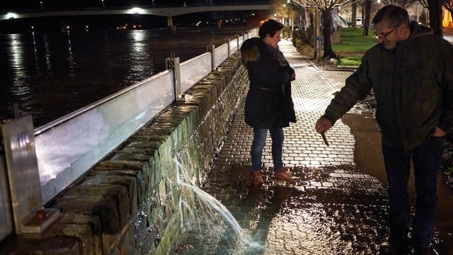 Ein Anwohner filmt mit seinem Handy in Zell eine Stelle an der Hochwasserschutzmauer, an der das Wasser der Mosel durch die Wand dringt.