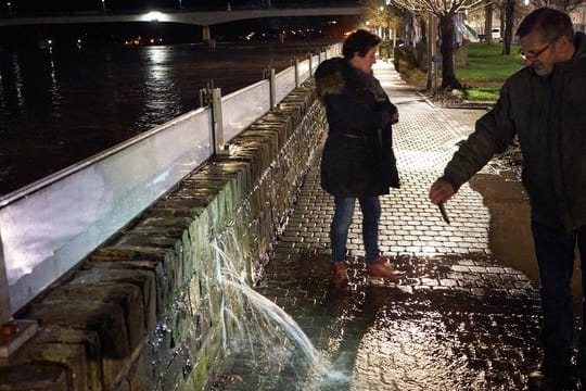 Ein Anwohner filmt mit seinem Handy in Zell eine Stelle an der Hochwasserschutzmauer, an der das Wasser der Mosel durch die Wand dringt.