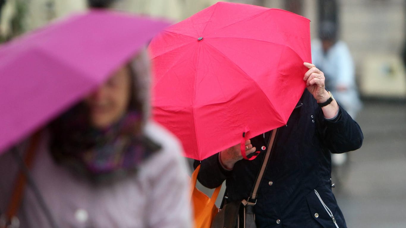 Frauen schützen sich mit ihren Schirmen vor dem Regen und starken Sturmböen (Symbolfoto): Auch in der nächsten Woche wird das Wetter ungemütlich.