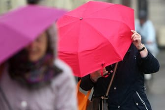 Frauen schützen sich mit ihren Schirmen vor dem Regen und starken Sturmböen (Symbolfoto): Auch in der nächsten Woche wird das Wetter ungemütlich.