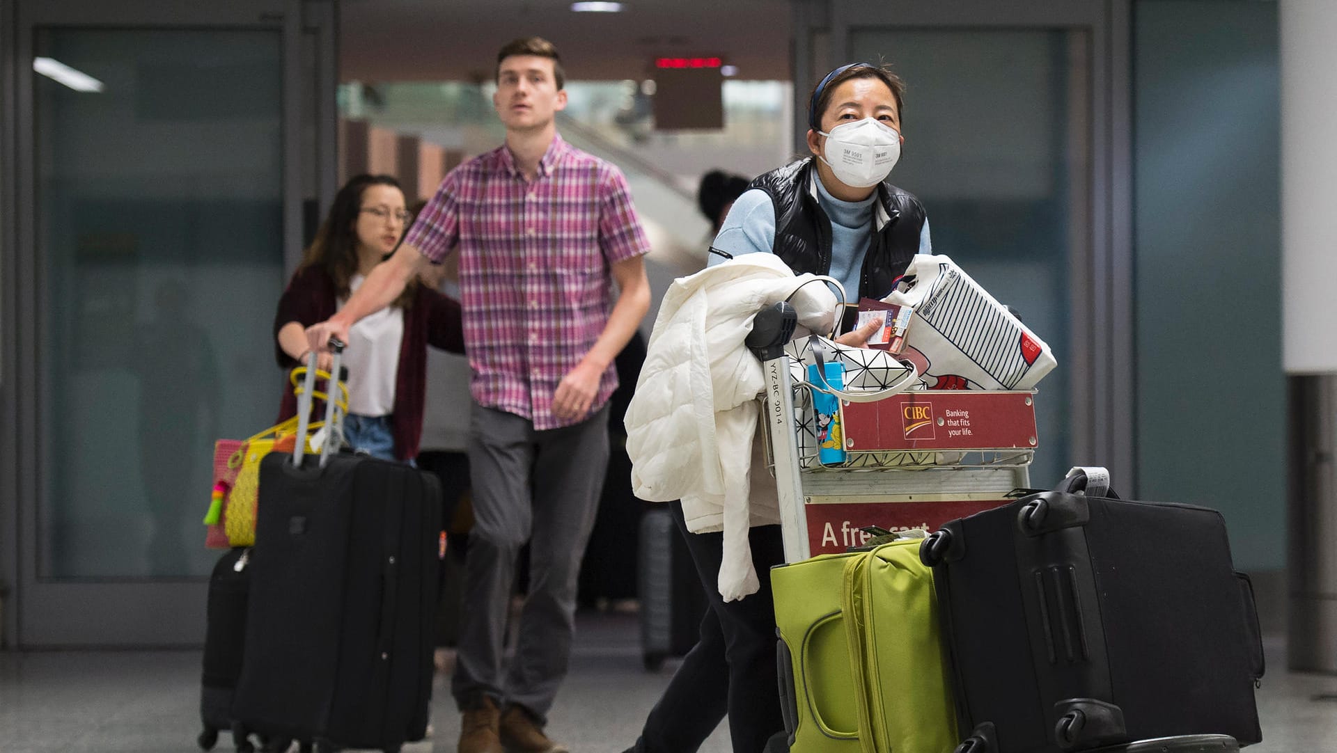 Reisende mit Mundschutz: Gegen die Verbreitung des Virus raten Experten auch, Abstand zu anderen Menschen zu halten.