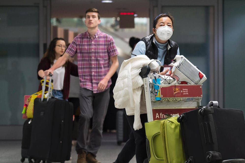 Reisende mit Mundschutz: Gegen die Verbreitung des Virus raten Experten auch, Abstand zu anderen Menschen zu halten.