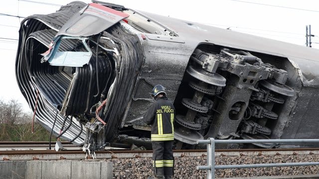 Ein Feuerwehrmann vor einem entgleisten Zugwaggon.