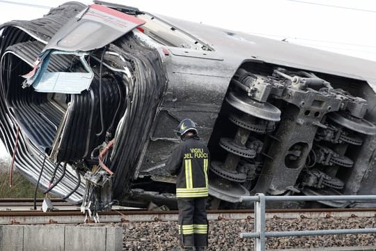 Ein Feuerwehrmann vor einem entgleisten Zugwaggon.