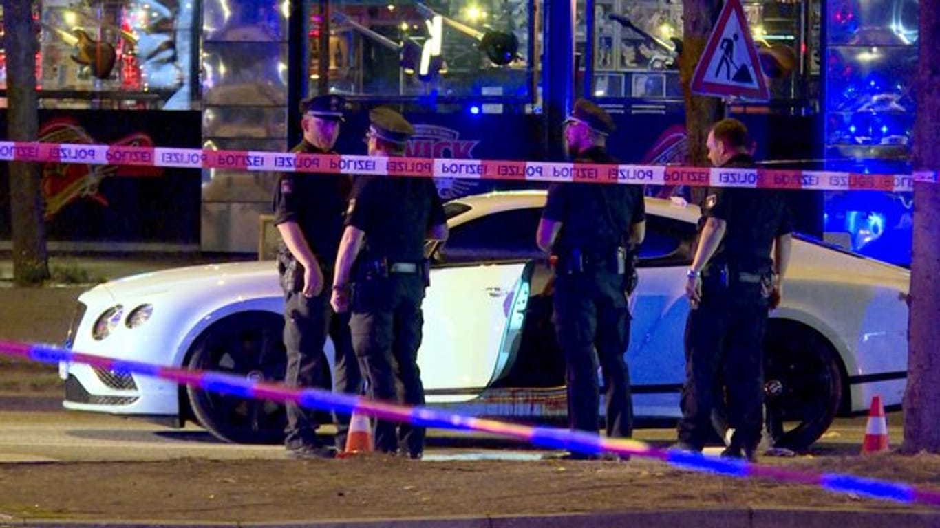 Polizisten stehen neben dem Auto des Rockerbosses auf dem Millerntorplatz an der Reeperbahn, nachdem die Schüsse gefallen waren.