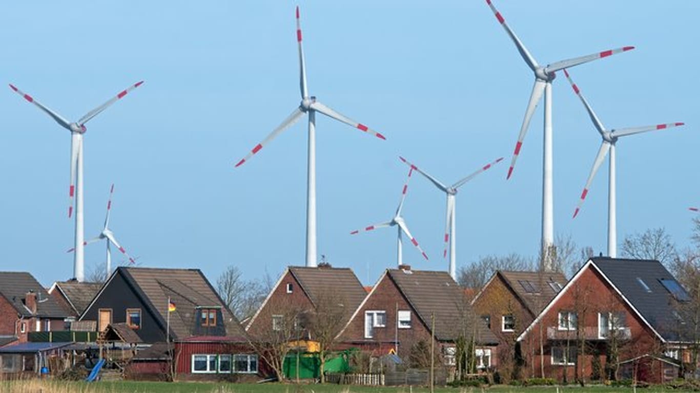 Windräder eines Windparks hinter einer Wohnsiedlung.