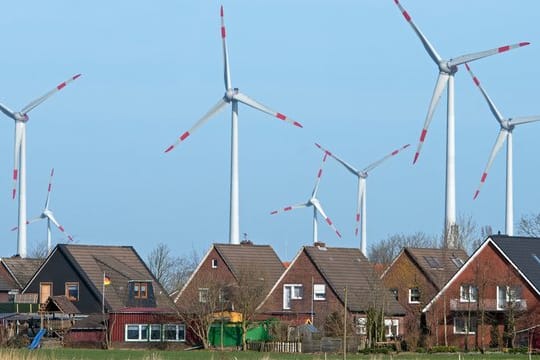 Windräder eines Windparks hinter einer Wohnsiedlung.