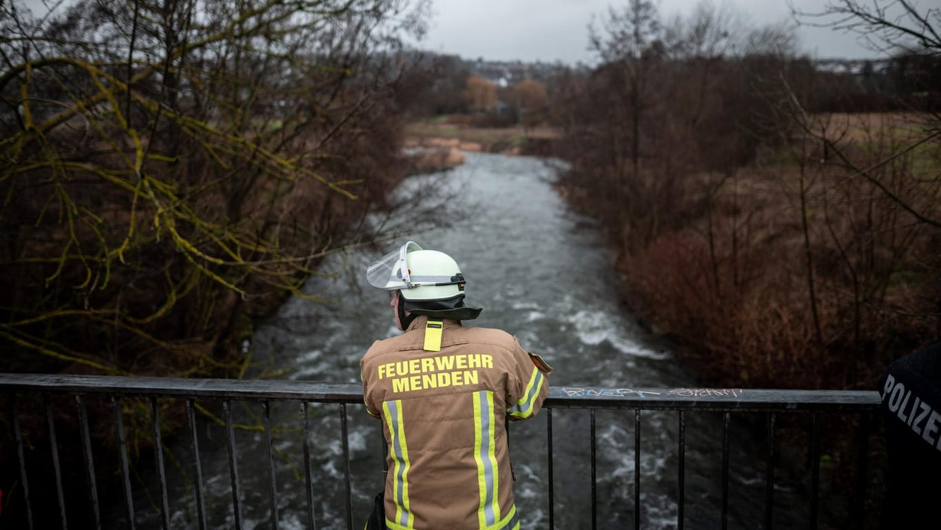 Ein Feuerwehrmann steht in Menden auf einer Brücke über die Hönne: Die Polizei schließt nicht aus, dass das Mädchen in den Fluss gefallen sein könnte.