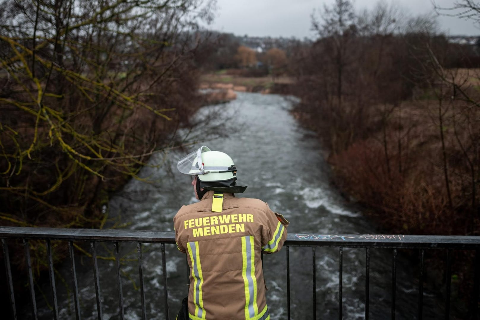 Ein Feuerwehrmann steht in Menden auf einer Brücke über die Hönne: Die Polizei schließt nicht aus, dass das Mädchen in den Fluss gefallen sein könnte.