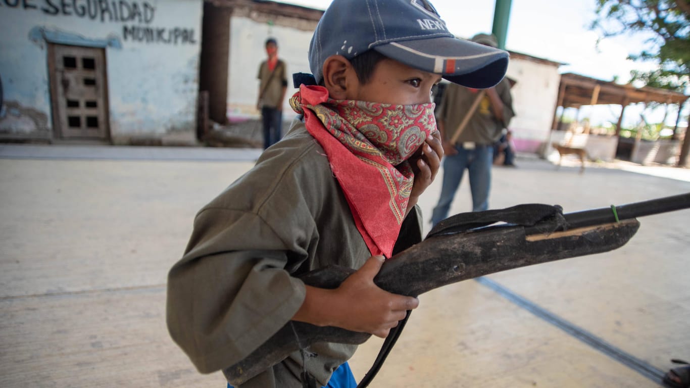 Eines der Kinder mit Mundschutz und Waffe: Viele der Kinder gehen nicht in die Schule, weil die Lage zu gefährlich ist.