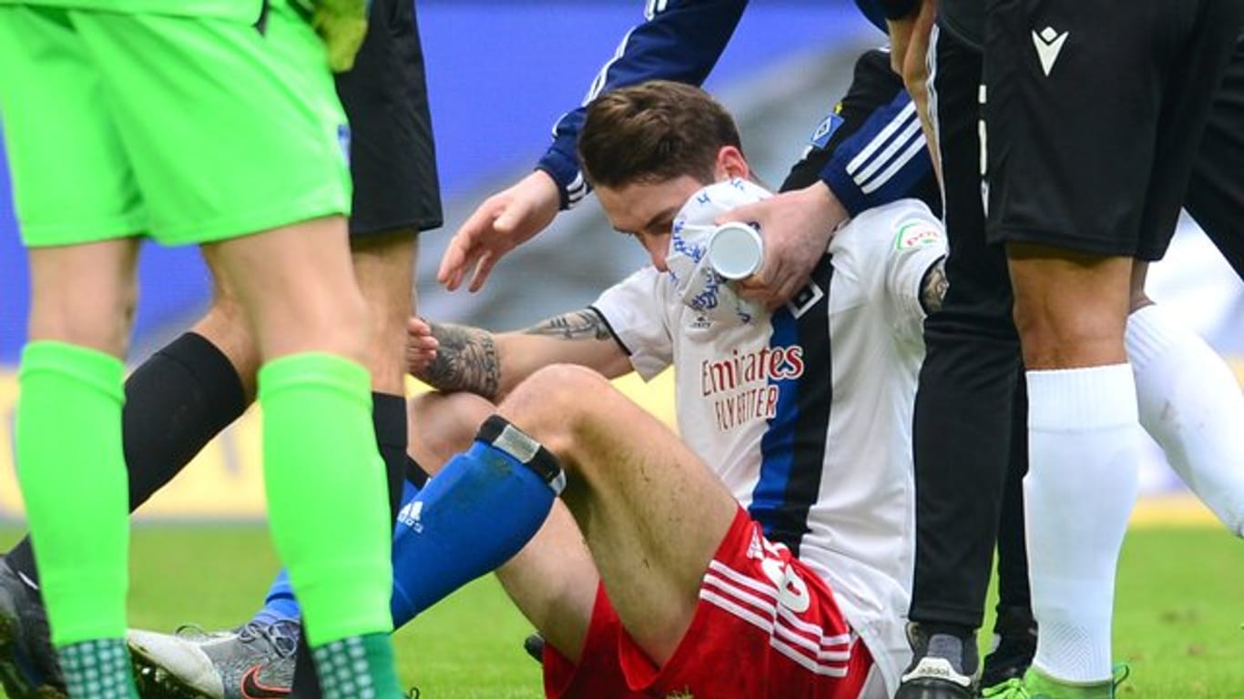 Hamburgs Adrian Fein sitzt verletzt auf dem Spielfeld und wird versorgt.