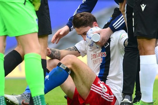 Hamburgs Adrian Fein sitzt verletzt auf dem Spielfeld und wird versorgt.