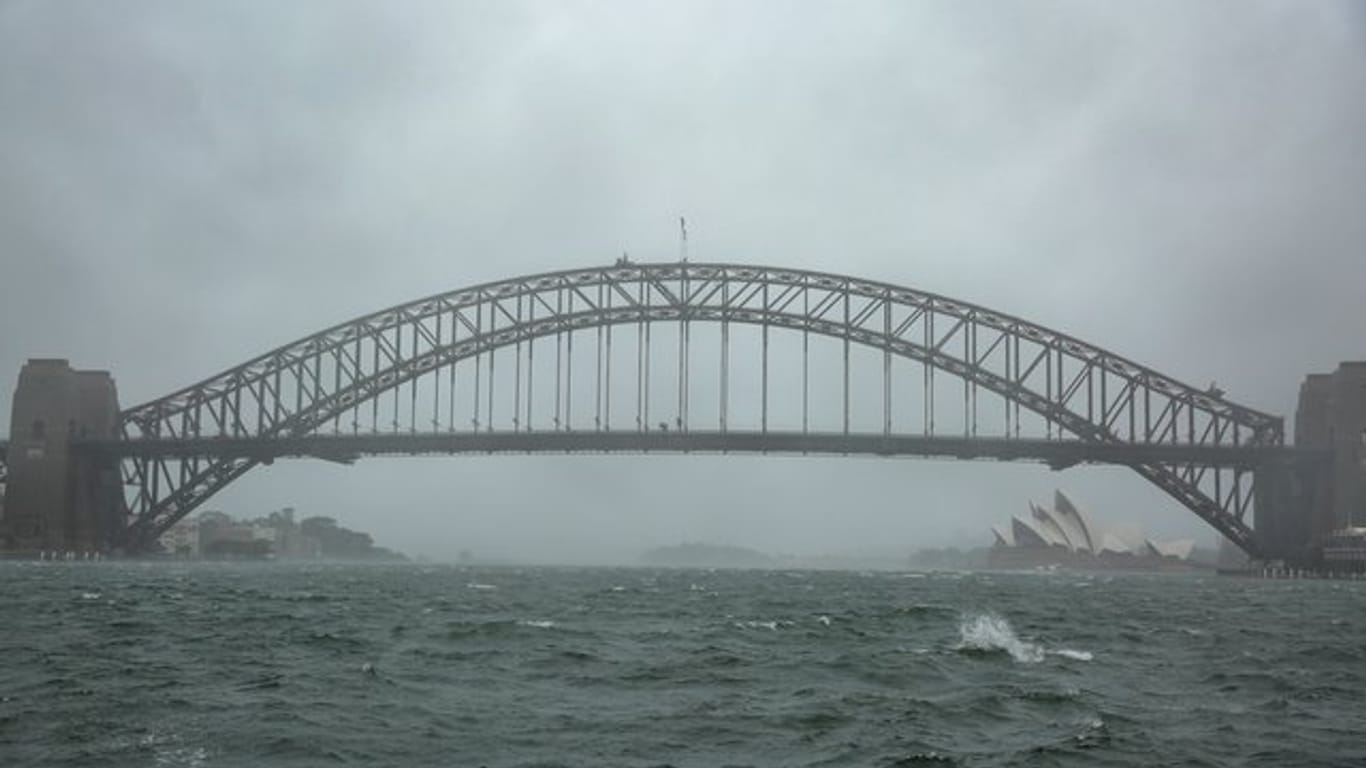 Winde peitschen das Wasser auf: Sydneys Harbour Bridge versinkt im Regenschleier.