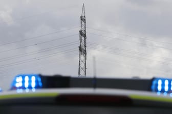 Polizeiauto vor einem Strommast: Am Montagmittag gab es ein Problem mit der den Rhein überspannenden Hochspannungsleitung. Der Fluss wurde für die Schifffahrt zwischen Düsseldorf und Krefeld gesperrt.
